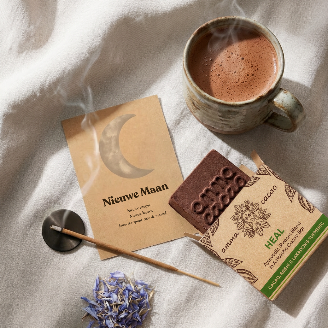 Nieuwe Maan cacao ritueel met Heal Amma Cacao bar, Nieuwe Maan intentiekaart met maansikkel, wierookstokje en blauwe bloemblaadjes.